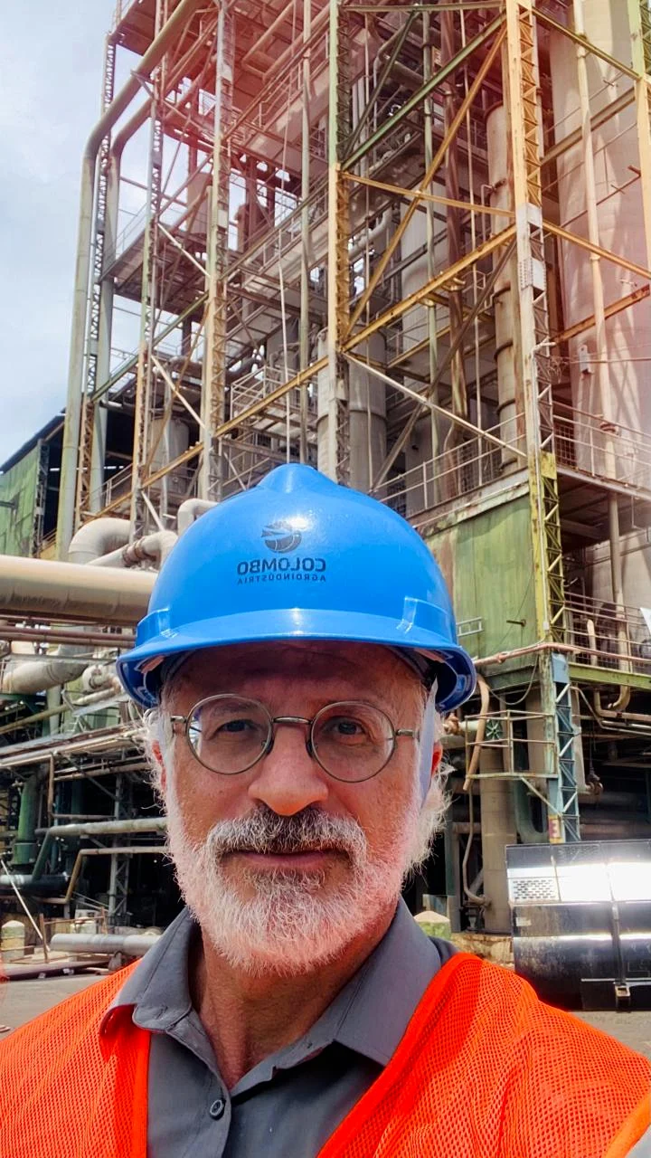 Tcharles Ferzoli em ambiente industrial, utilizando capacete e equipamento de segurança